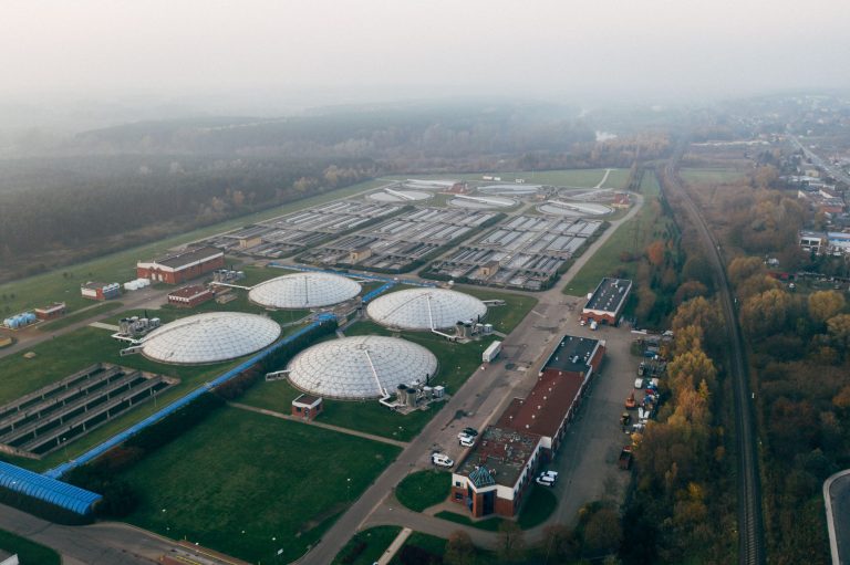 Vista aérea de uma estação de tratamento de águas residuais, com tanques e estruturas industriais.